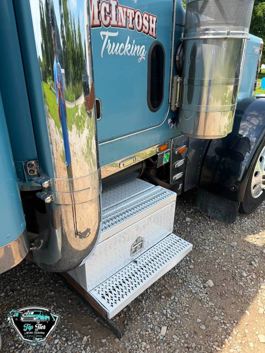 Close view of a polished chrome exhaust stack and bright diamond plate step box on a semi truck