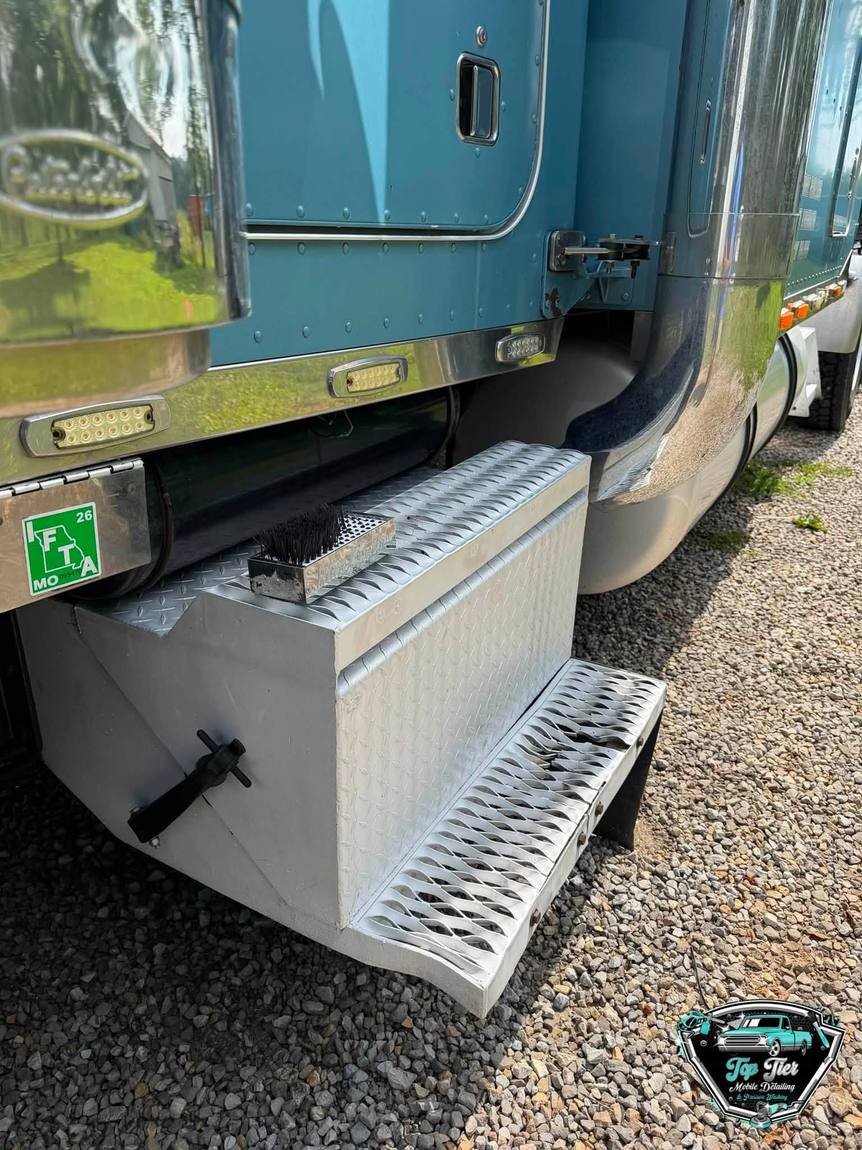 A washed step box and lower cab panels on a blue semi truck